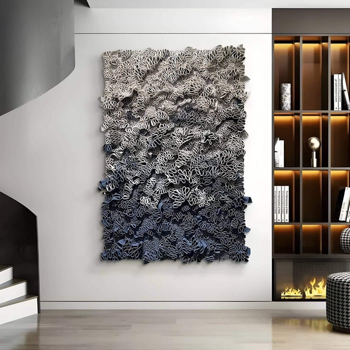 Large vertical 3D wall art with intricate ribbon-like leather forms in a gradient from light beige to deep blue, mounted in a modern living space beside open shelving with warm accent lighting.