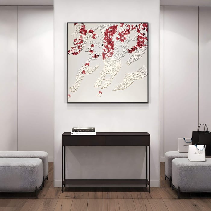 Square 3D wall art featuring layered white and crimson leather scales arranged in a flowing, abstract pattern, displayed above a dark console table in a sleek modern hallway.