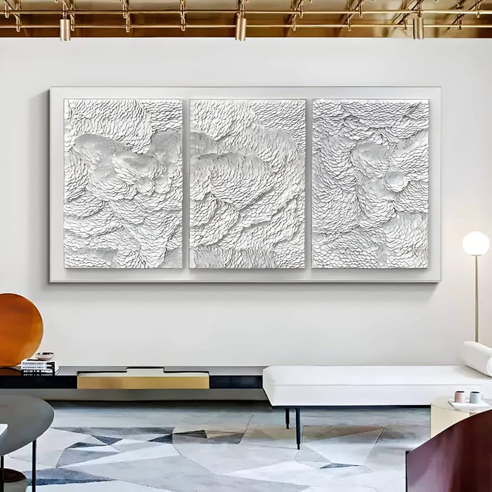 Three-panel white 3D wall art with intricate swirling leather textures, creating a cloud-like abstract design, displayed in a modern living space with gold ceiling accents and minimalist furniture.