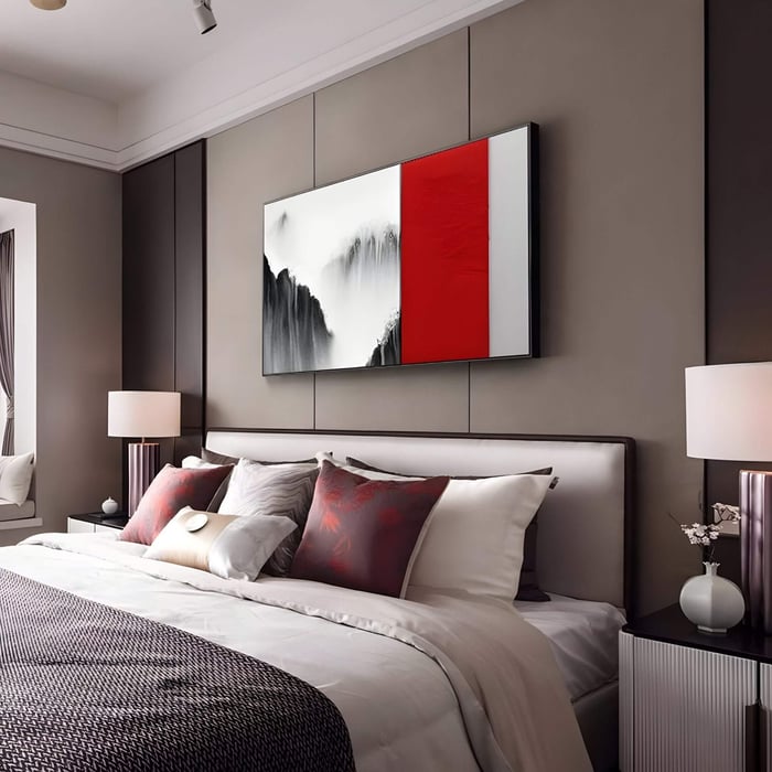 Rectangular 3D wall art featuring a black and white waterfall ink-style scene with a bold red leather carving panel, mounted above a modern bed with layered cushions in a soft-toned bedroom.