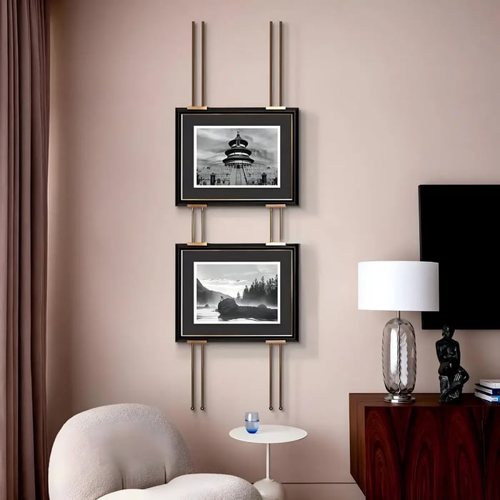 A sophisticated corner with two vertically stacked black-and-white framed landscape photographs, elegantly mounted with gold detailing.