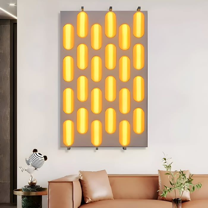 Wall-mounted panel of glowing yellow capsule-shaped lights above a modern tan sofa in a contemporary living room.