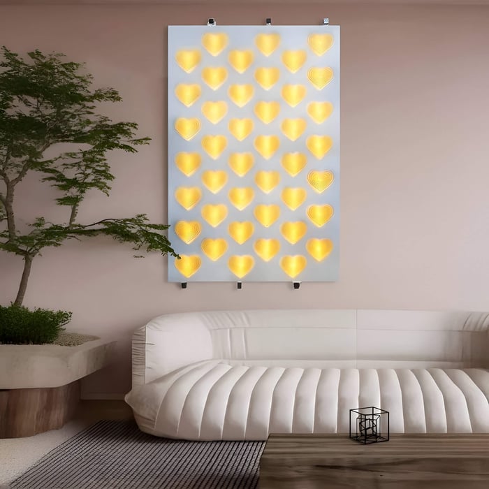 Wall-mounted panel of glowing yellow heart-shaped lights above a curved white sofa in a modern living room with a potted tree and wooden coffee table.