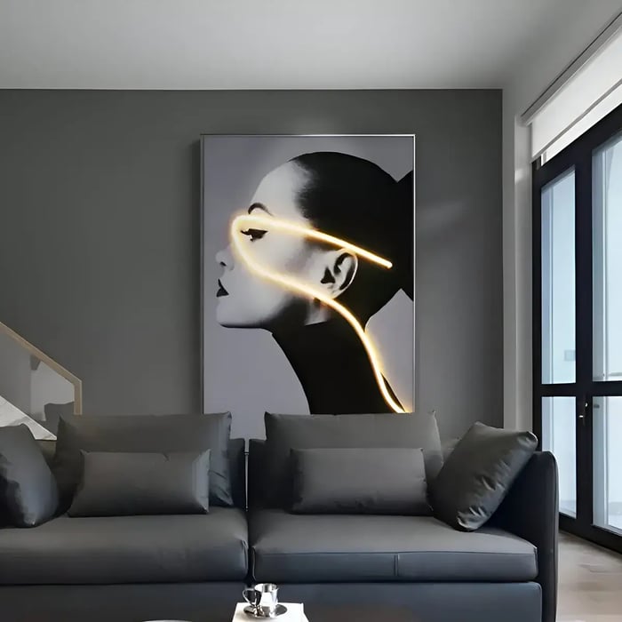 A dramatic black-and-white portrait of a woman, highlighted by a glowing neon light tracing her face, adding a futuristic touch to a dark-toned interior.