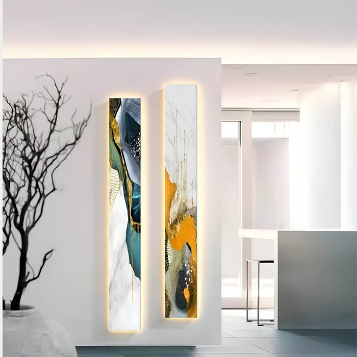 A modern hallway adorned with two vertical abstract paintings featuring gold, blue, and white textures, illuminated for a striking effect.