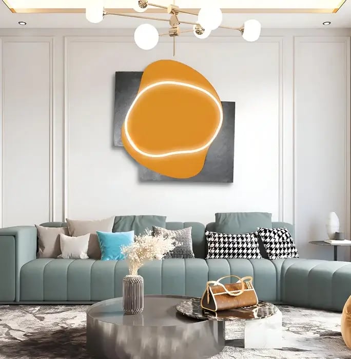A modern living room featuring an abstract orange and white illuminated wall art piece above a sleek teal sofa with stylish decor accents.