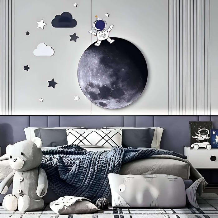  Whimsical kids' wall art featuring a moon, stars, clouds, and an astronaut above a cozy, toy-filled bed.