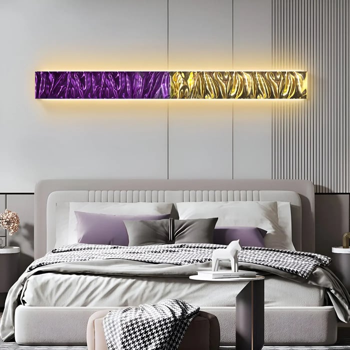 A sophisticated bedroom featuring a long horizontal metallic wall panel in gold and deep purple tones, backlit with warm LED lighting above a plush bed.