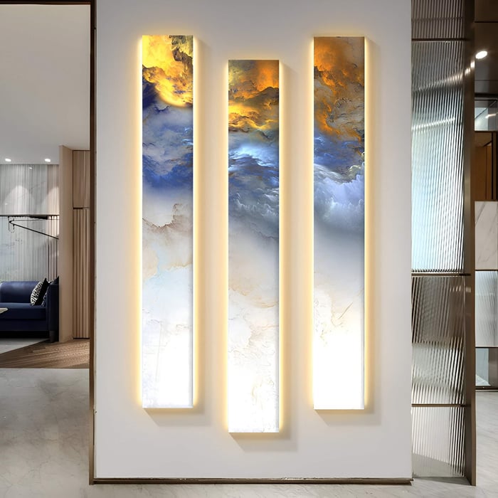 Three tall vertical panels in white and gold abstract patterns with integrated lighting, making a dramatic statement in a minimalist white hallway.