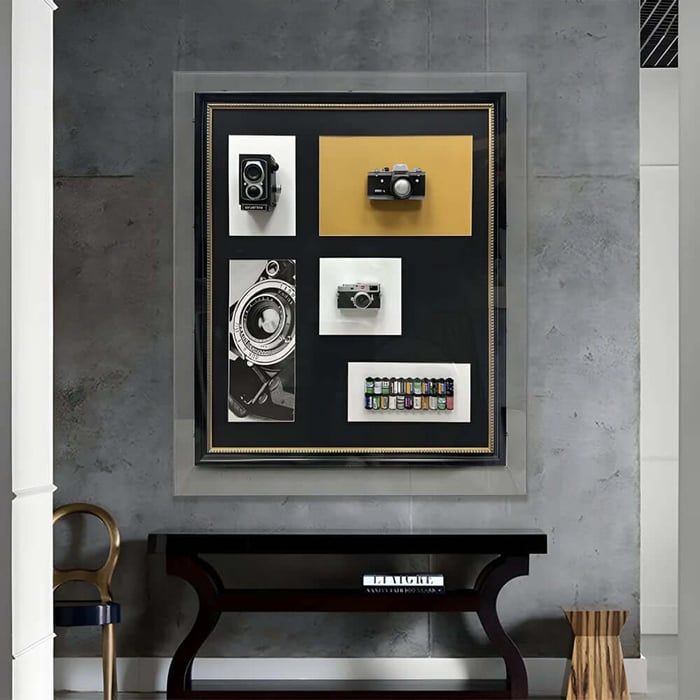 Large framed collage artwork featuring vintage cameras and film displayed above a console table.