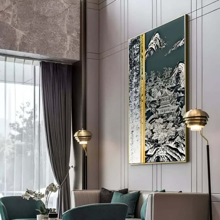 Elegant modern living room with tall grey paneled walls, brass floor lamps, and a large vertical framed artwork featuring a dark green landscape-inspired design with gold accents above a sofa and teal chair.