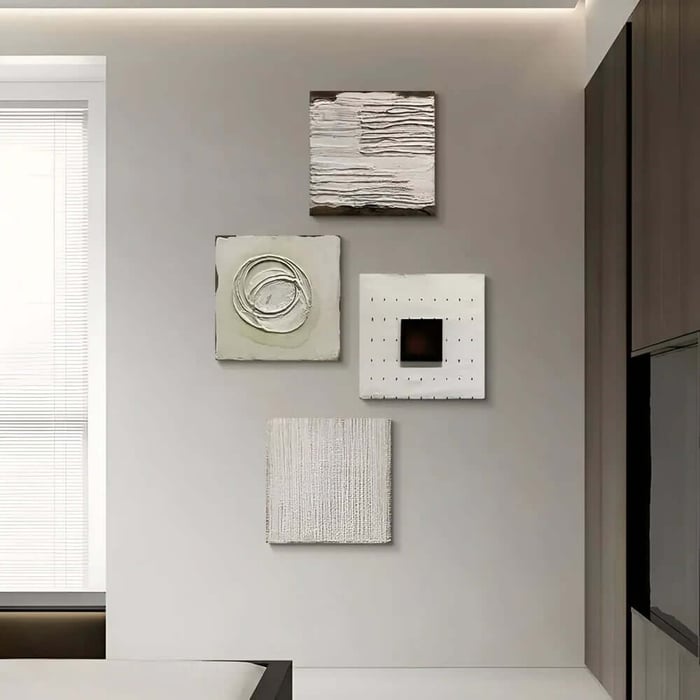 Set of four minimalist textured wall pieces arranged in a grid on a grey wall in a contemporary home.