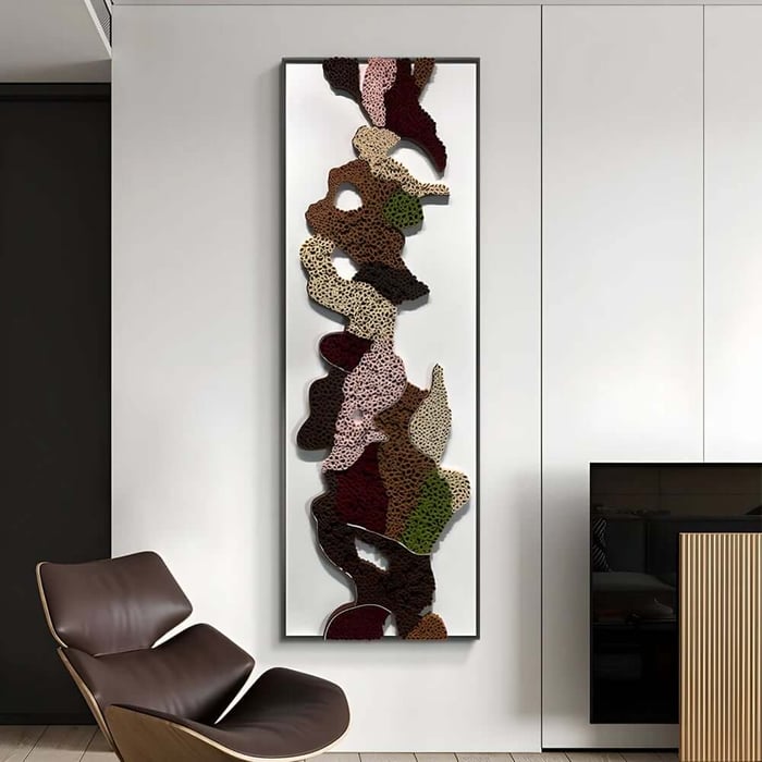 Tall framed abstract wall art with layered organic cut-out shapes in earthy tones, displayed in a modern minimalist interior.