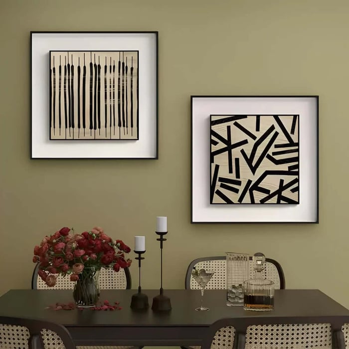 Two framed black-and-white abstract prints on olive dining room wall above table.