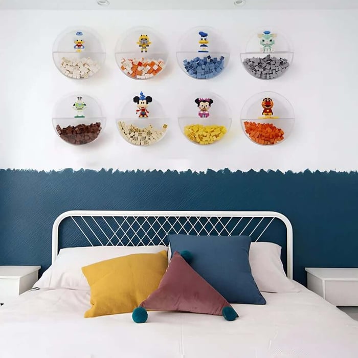 Clear wall-mounted bubble shelves filled with colourful LEGO bricks arranged in a neat grid above a bed