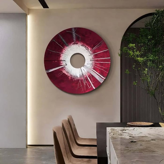 Large red circular abstract wall art with white centre above modern dining chairs.