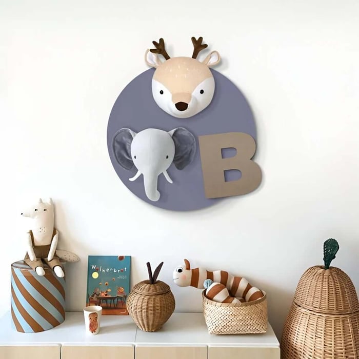 Grey circular kids wall plaque with deer and elephant heads and letter B displayed above a toy cabinet.