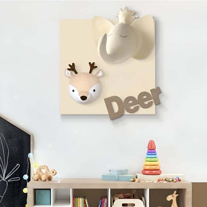 Neutral animal nursery wall art with elephant and deer heads and the word “Deer” above toy storage.