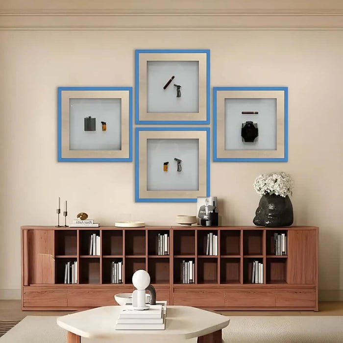 Four blue-framed shadowboxes with small objects arranged in a grid above a wooden cabinet.