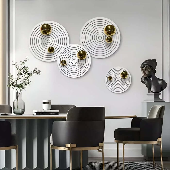 Modern dining room wall art set of white discs with gold accents above table.