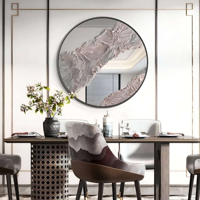Round wall mirror with textured neutral abstract in elegant dining space.