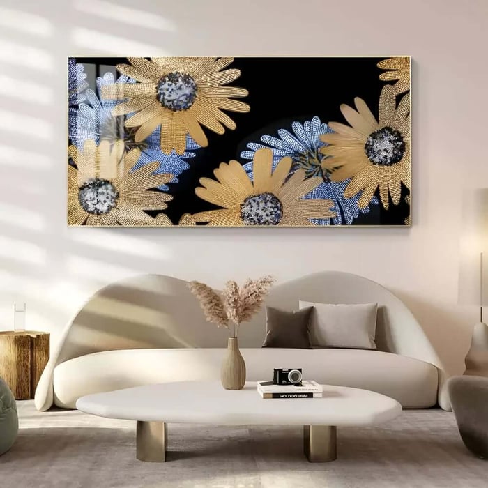 Oversized floral wall art with golden daisies on a black background above a curved cream sofa in a bright living room.