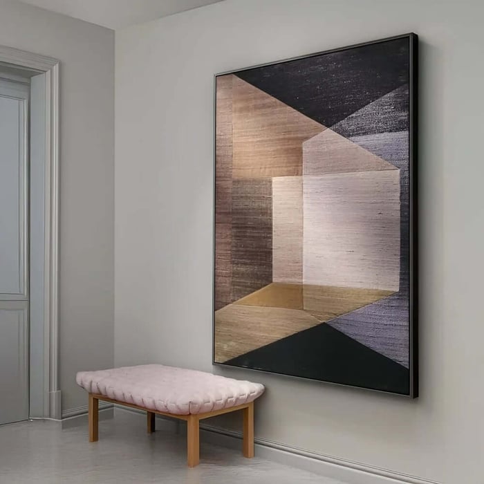 Muted geometric hallway painting in beige, taupe and black next to a soft pink bench.