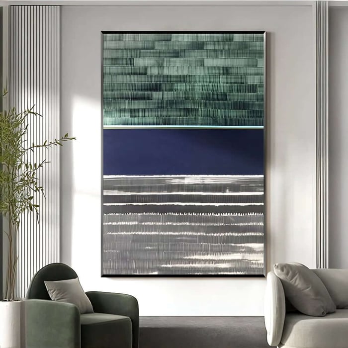 Large framed abstract artwork with layered green, navy, and grey horizontal bands displayed in a modern lounge with armchairs and soft daylight.
