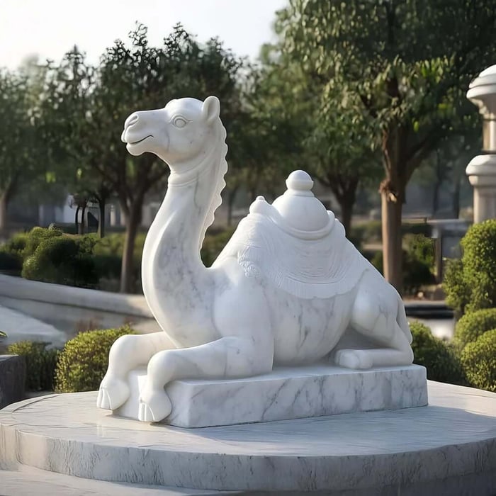 White marble camel sculpture on a circular plinth in a landscaped garden.
