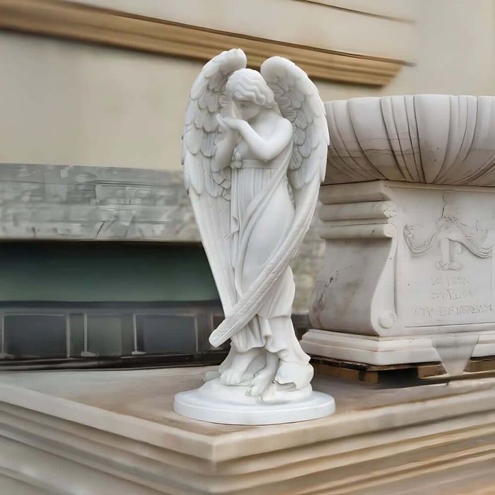 Small marble angel statue with folded hands displayed beside a stone fountain base.