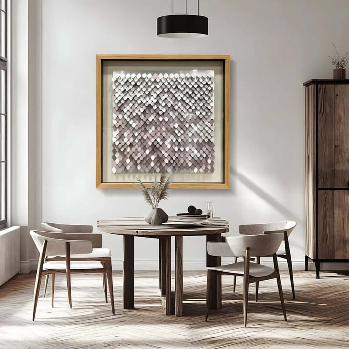 Framed textured wall art above a wooden dining table in a bright modern room.