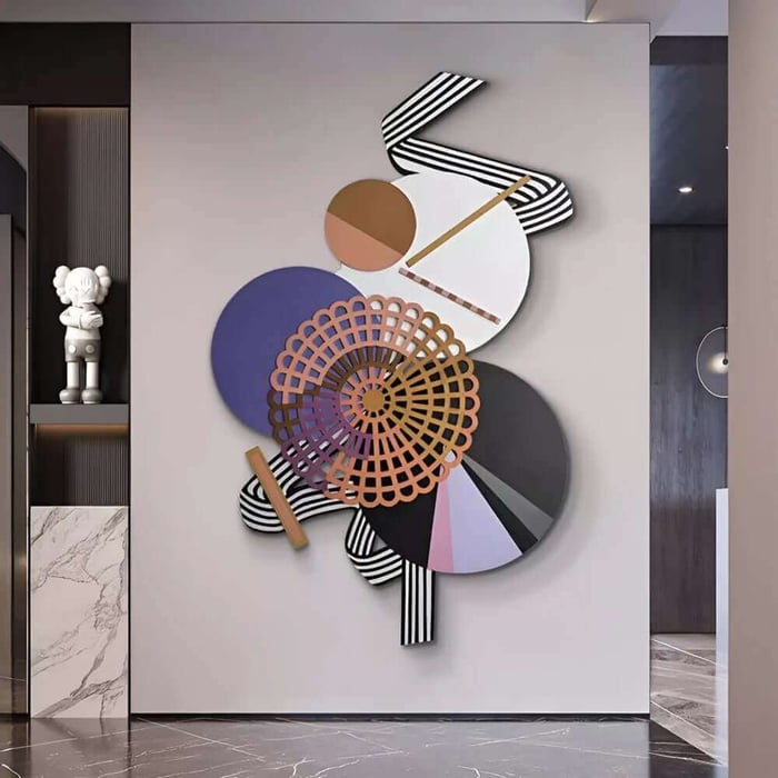 Modern hallway interior featuring a large colourful abstract 3D wall sculpture made of overlapping circles, stripes, and lattice shapes mounted on a light grey wall.