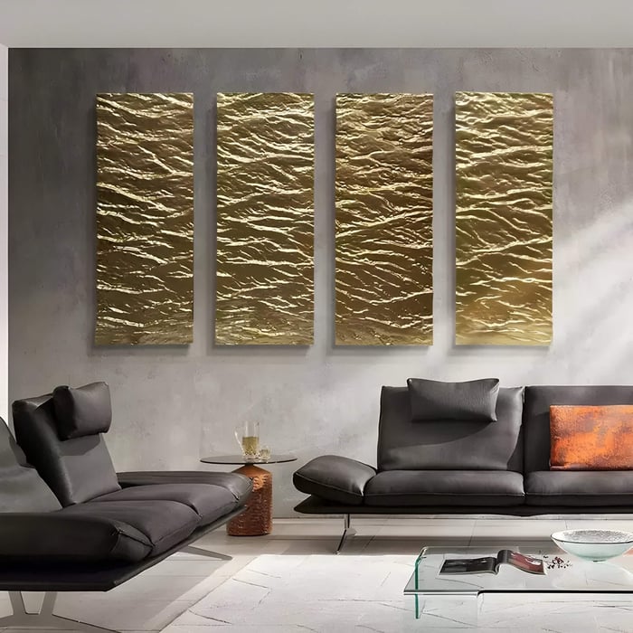 Modern living room with four-panel gold 3D wall art mimicking water ripples, set above sleek black leather sofas and a glass table.