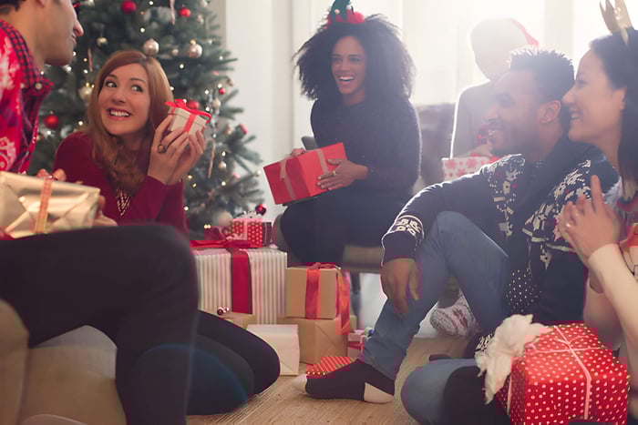 friends opening christmas gifts around a christmas tree