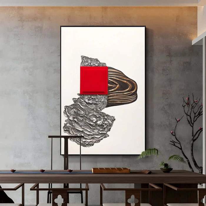 Large modern statement artwork with a bold red square accent mounted on a textured grey wall above a long table.