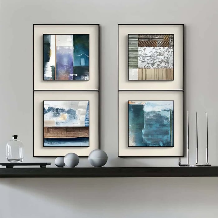 Four framed abstract prints in blue and neutral tones displayed in a neat grid above a minimalist shelf.