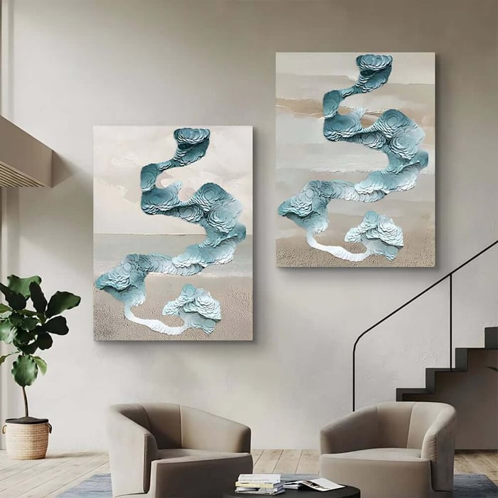 Two-panel abstract artwork with raised teal, ribbon-like forms on sandy neutral backgrounds above modern armchairs by a staircase.
