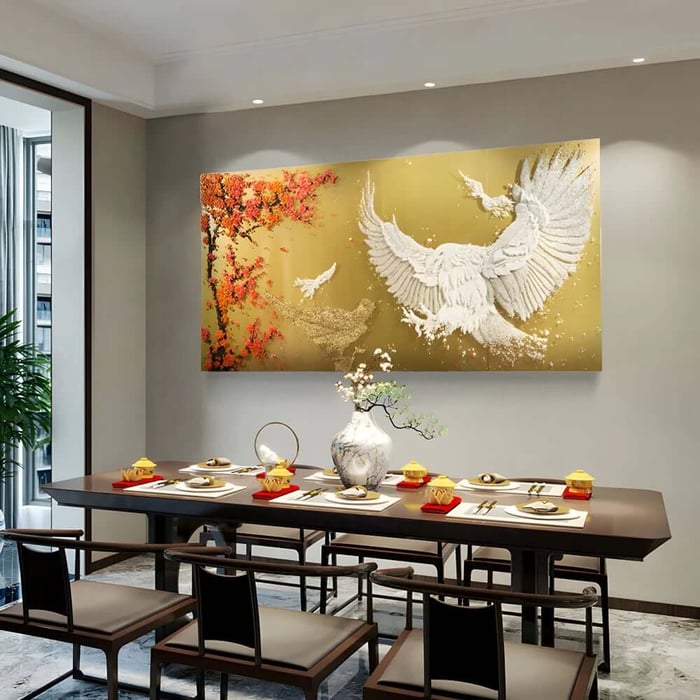 Golden wall artwork featuring a white bird with spread wings and red blossom accents above a dining table set for guests.
