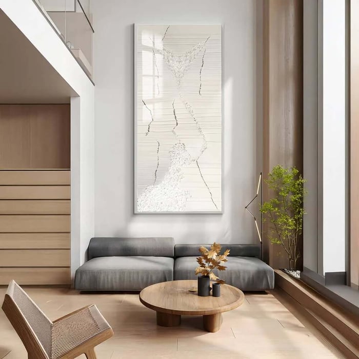 Tall white textured abstract canvas with fine crack-like lines above a grey sofa in a bright, minimalist living room with light wood flooring.