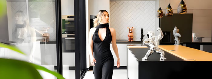 A modern home featuring a luxury chrome gorilla sculpture with a woman walking past admiring the sculpture