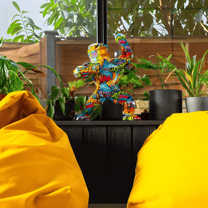 a multi coloured pop art gorilla sculpture in a brightly coloured home with plants