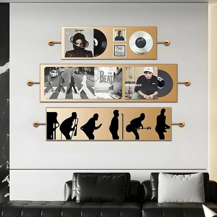 Music-inspired wall art arrangement in a contemporary space – A set of framed vinyl records and iconic album imagery displayed above a sleek black leather sofa.