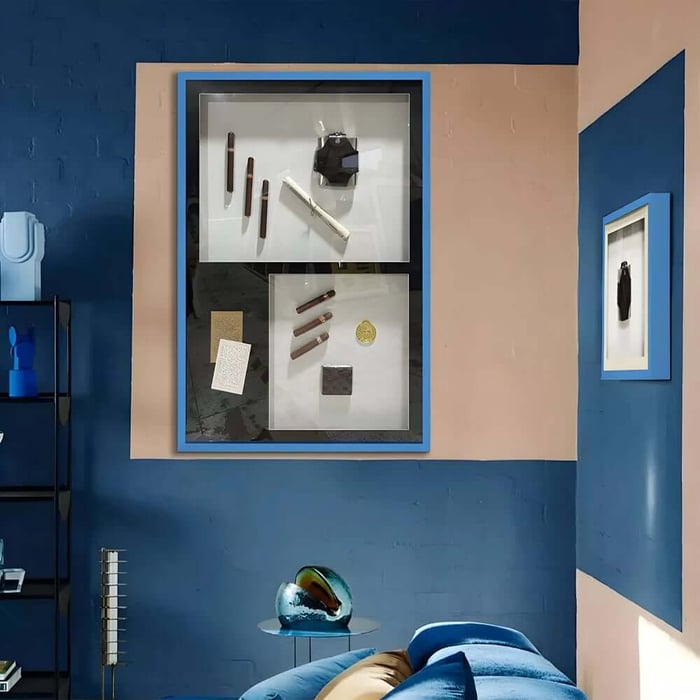 Blue room interior featuring a framed display-style artwork with objects arranged in compartments.