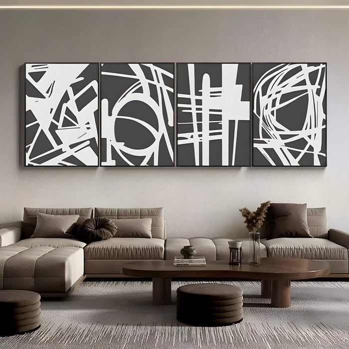 Four-panel abstract wall art featuring bold white geometric line patterns over a dark grey background, displayed in a modern living room above a sectional sofa.
