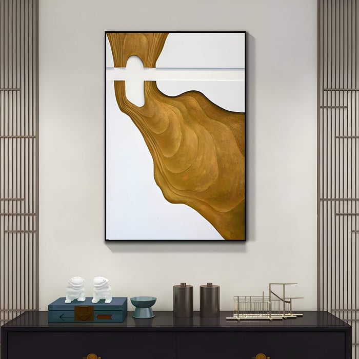 Framed abstract 3D wall art featuring a flowing golden carved form set against a clean white background.