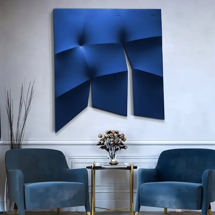 A bold and contemporary lounge area with a deep blue three-dimensional geometric wall sculpture mounted above a seating area with matching blue velvet chairs and a gold-accented coffee table.