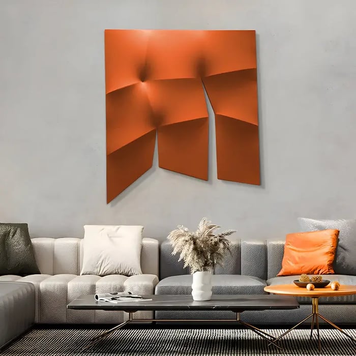 A bold, three-dimensional orange wall sculpture displayed in a contemporary living room with a neutral-toned sofa and accent pillows.