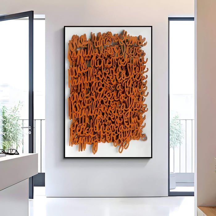 The Oratoria Orange Scripted Wood Art by Giant Sculptures is showcased in a well-lit room with large windows and minimal decor. A potted plant seen through the window adds to the airy, contemporary ambiance.