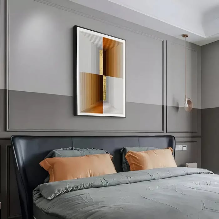 A contemporary bedroom featuring a black leather bed with muted green bedding and orange accent pillows, complemented by a geometric abstract artwork in warm tones above the headboard. 