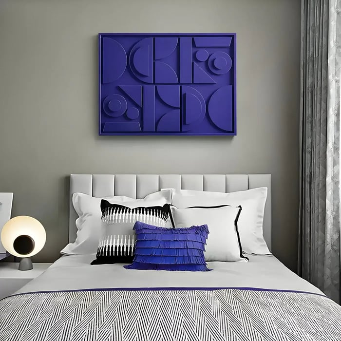  A contemporary bedroom with a statement silver wall sculpture, featuring a split circular design with textured surfaces, mounted above a bed with houndstooth and neutral bedding.